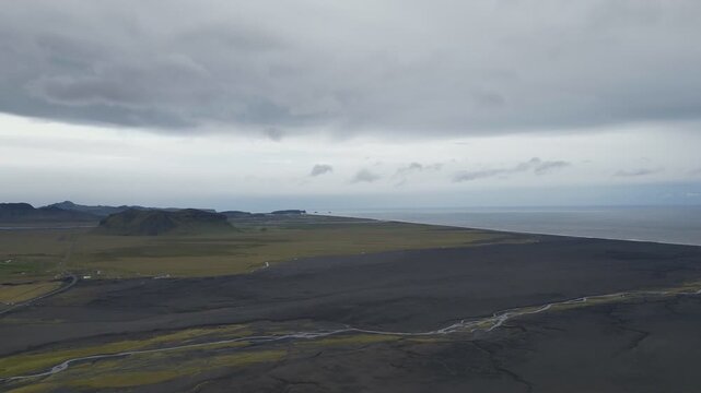 A slender river snaking through dark, moody rolling hills in Iceland.