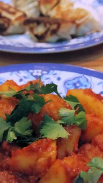 Taking a piece of Nepali aloo dum or spicy potato curry topped with cilantro at a restaurant in Central, Hong Kong 