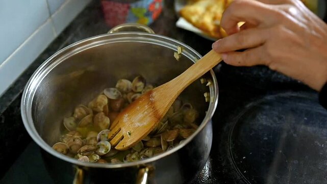 Cooking garlic clams in white wine on the kitchen at home,  seafood recipe Mediterranean cuisine gourmet homemade cooking parsley finishing touch