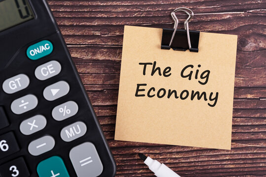 Calculator and The gig economy text on brown memo pad