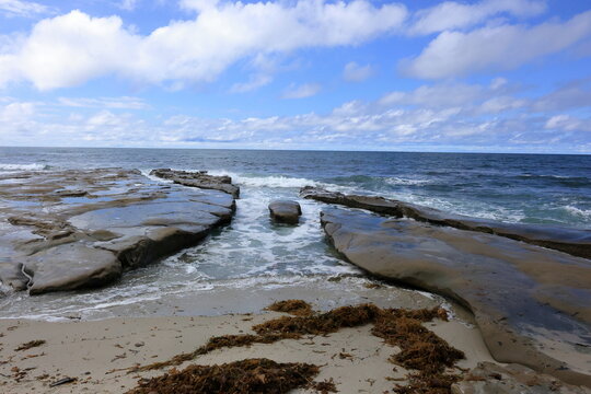 Sandy Beach with Seaweed Along Shoreline Under Clear Sky