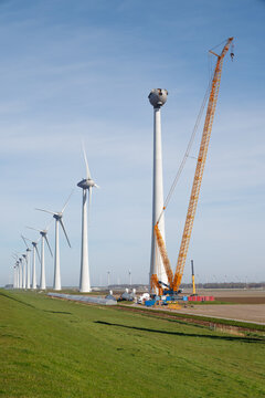 Wind turbines under construction with crane in polder landscape