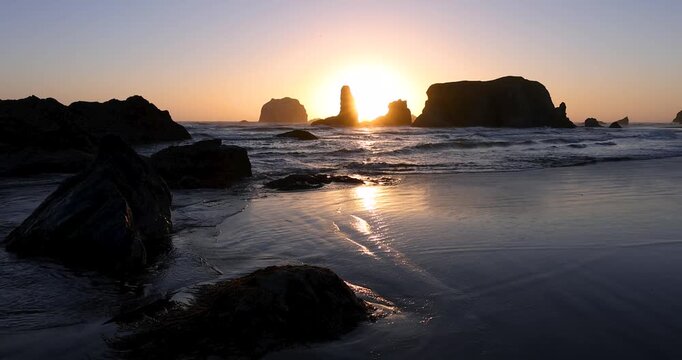 Scenic sunset over the Oregon coast sea stacks with waves washing over wet sand