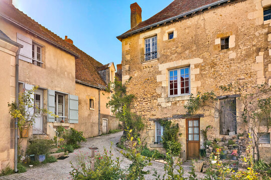 Beautiful streets of Montresor in the Loire Valley of France. Picturesque stone houses, leafy vines and flowers under golden late day light.