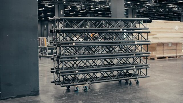Video of Black Stage Truss Structure on Caster Wheels in Large Exhibition Hall &mdash; Production Equipment Ready for Assembly in Empty Industrial Event Space