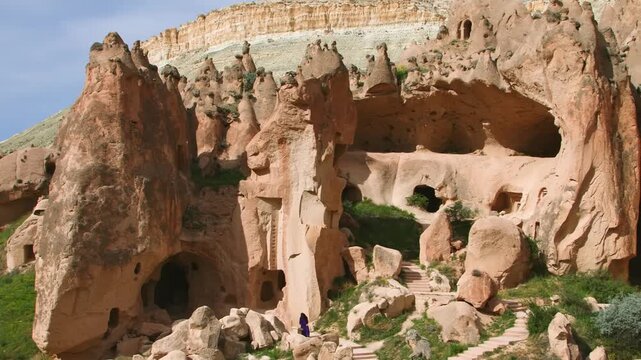 A tourist explores the dramatic, historical landscape of the Zelve Open-Air Museum in Cappadocia, Turkey. The region is famous for its extraordinary tuff rocks, also known as "fairy chimneys," and anc