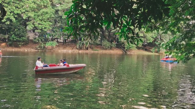 People enjoy a leisurely boat ride on a calm 05 September 2025 at Dhaka Dhanmondi lake surrounded by lush green trees and foliage.