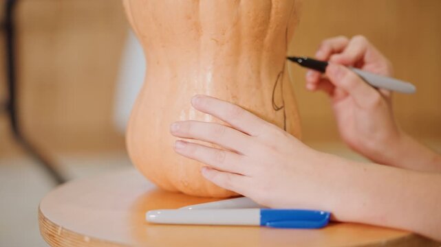 Hands marking pumpkin on wooden turntable, artisan baker sketches pie design, food stylist traces pattern, craft artist prepares carving guide, food photographer captures closeup, home cook plans