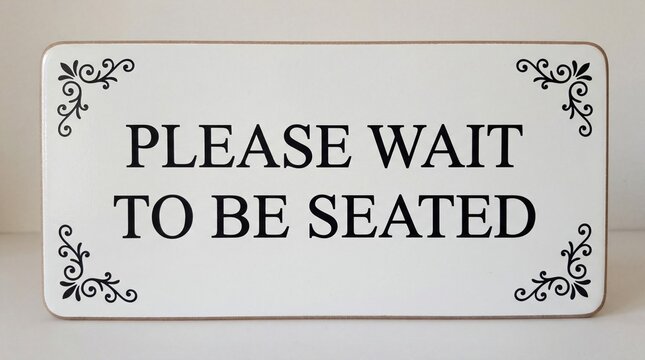 A sign that says please wait to be seated in a restaurant or cafe