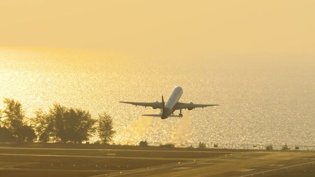 Passenger airplane departure at Phuket airport, yellow sunset light.
