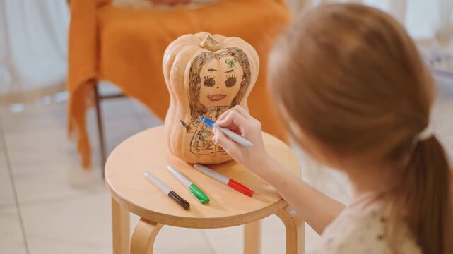 White girl coloring pumpkin with markers on small table, lively home craft scene, colorful marker set on tabletop, bright warm light, energetic focus, hands creating whimsical face and patterns