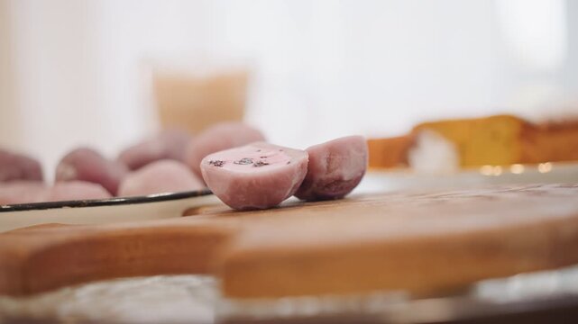 Closeup purple potato slice on board, soft morning light, blurred glass and toast in background, shallow depth of field highlights textured flesh and speckled skin, rustic breakfast prep scene