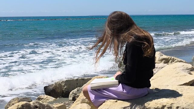 Young Christian Teen Girl Reading Bible by the Rocky Seashore - Slow Motion Half Speed