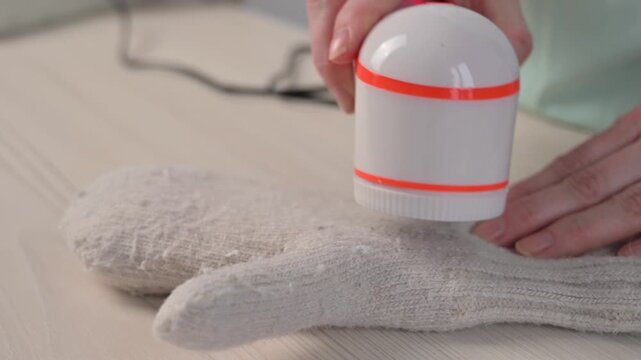 A woman revives the look of her knitted garments with a lint remover.