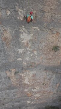 Deportista extremo bajando rapel  por una enorme pared de roca