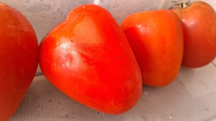 Three vibrant red tomatoes arranged neatly on a surface to represent healthy organic raw produce © Sueliton