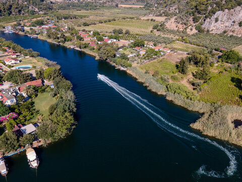 Aerial view of Dalyan town and river with boats moving on water. Coastal settlement, summer tourism, waterfront lifestyle, scenic landscape and travel destination concept. Ortaca, Mugla