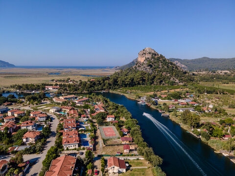 Aerial view of Dalyan town and river with boats moving on water. Coastal settlement, summer tourism, waterfront lifestyle, scenic landscape and travel destination concept. Ortaca, Mugla