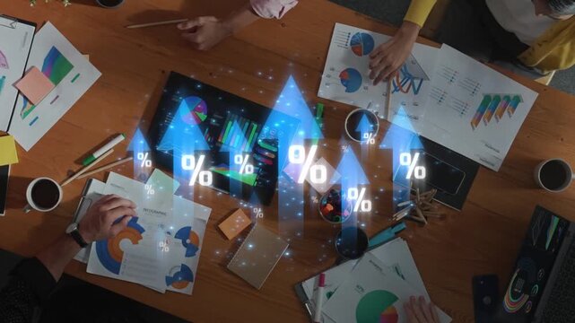 A diverse team collaborates in an office environment, analyzing financial data with graphs and charts, aiming for effective strategies and improved business performance. Raster