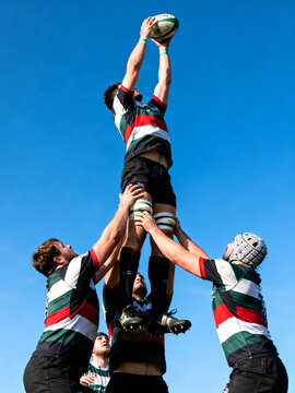 Rugby lineout jump during competitive match, professional rugby players lifting teammate for ball possession, athletic team sports action isolated on White Background