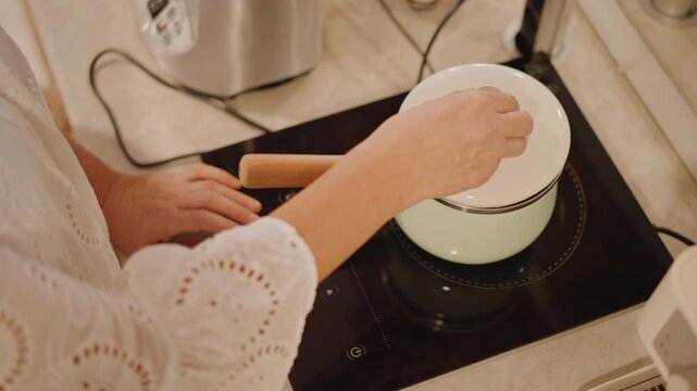 Home cook steams pumpkin chunks stovetop, enamel saucepan with wooden handle, hands lifting lid, diced orange squash simmering for pie filling, warm countertop, kettle in background, soft autumn