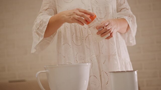 Closeup hands cracking egg into bowl for pumpkin pie filling, woman wearing lace dress preparing batter in ceramic mixing bowl, vintage measuring cup beside bowl, warm golden light, calm cozy autumn