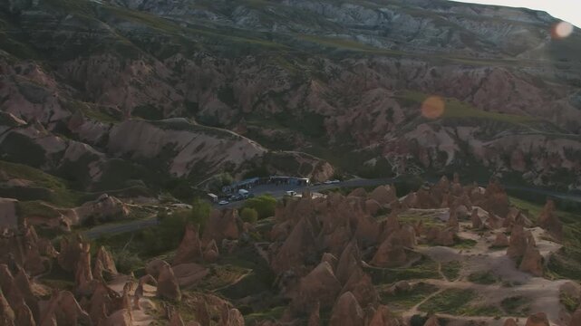 aerial shot captures the magical and moon-like landscape of the famous Red Rose Valley in Cappadocia, Turkey. The video showcases the region's iconic "fairy chimneys" and ancient rock formations, scul