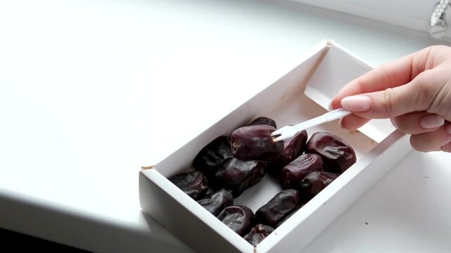 use a white plastic fork to remove dates from the box. High quality 4k footage