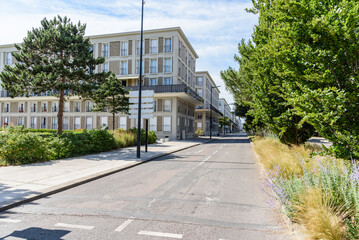 Empty straight street lined with rows of apartment buildings in a city centre on a sunny summer day © alpegor