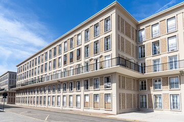 Exterior of a historic apartment building under blue sky in summer. Post war modernist architecture. © alpegor