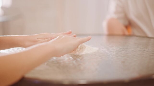 White hands dusting flour on table, parent and child shaping mound for pumpkin pie dough in sunlit kitchen, gentle teaching gestures, warm tones, closeup texture of flour, slow careful motion