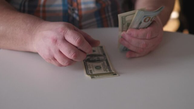 Individual Handling Cash Meticulously, Man Systematically Stacking Dollar Bills In Welllit Studio, Man In Plaid Shirt Carefully Arranges Cash On Brightly Illuminated Table For Management