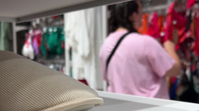 Defocused video. 60 fps. Out of focus white woman in pink t-shirt choosing lingerie, bra in female clothing retail store. Blur. Concept of Black Friday sale, 11 november, buying clothes, shop, fashion