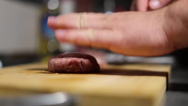 Defocused 4K video close up. Chef makes, forms round burger patties, cutlet of ground beef, minced meat, pork, lamb with hands on wooden cutting board on kitchen table. Health food preparation. Cafe