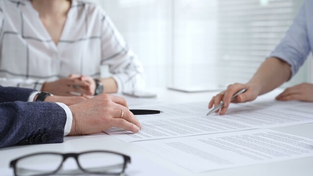 Business people discussing contract details during an important corporate meeting, partners reviewing legal documents with an attorney, collaborating on an agreement