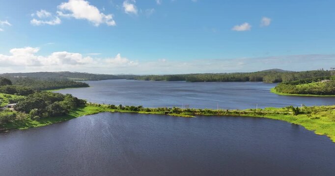 4K aerial drone view of Alto Tiete reservoir in Brazil, showing water storage, rural landscape, forests and agricultural fields under blue sky