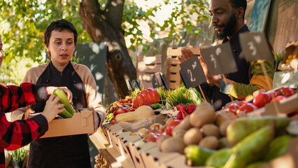 Senior man and young woman buying organic bio products, visiting local farmers market stand. Smiling vendors greeting customers and selling homegrown fruits and veggies from farm. © DC Studio