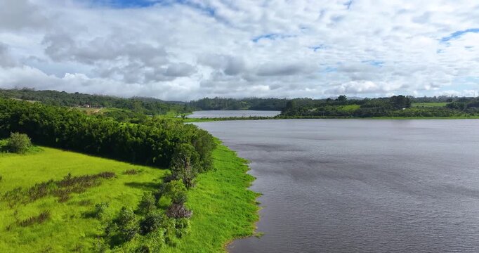 4K aerial drone view of Alto Tiete reservoir in Brazil, showing water storage, rural landscape, forests and agricultural fields under blue sky