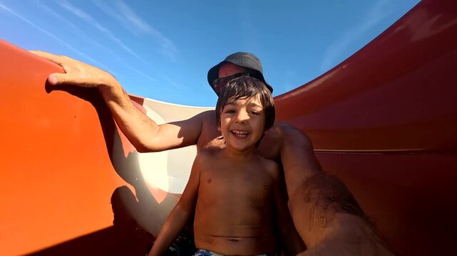 Father and son sliding down waterslide together