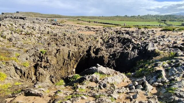 People walking near the bufones de pria sinkholes in llanes, spain