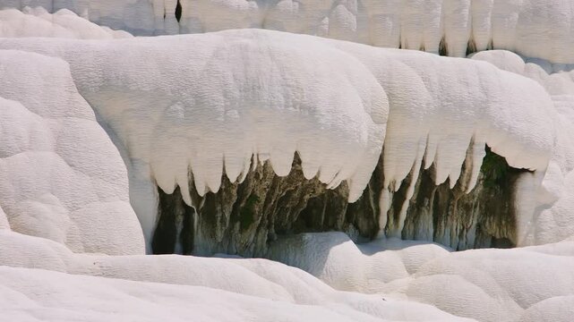 A high-detail view of the unique, snow-white travertine terraces and mineral formations at Pamukkale, Turkey. These natural limestone pools were sculpted over thousands of years by calcium-rich therma