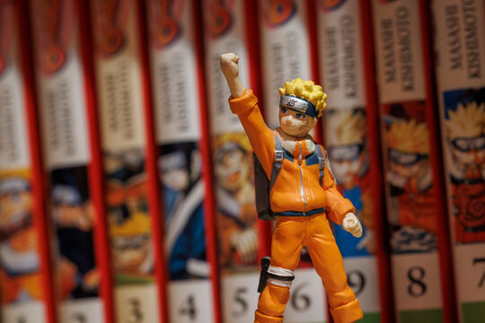 OURENSE, SPAIN - APRIL 11, 2026: Figure of Naruto Uzumaki with blurred Naruto manga volumes in the background, illustrating Japanese pop culture and collectible fandom.