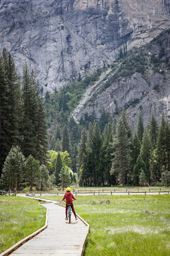 Young person riding bike on a wooden pathway in Yosemite Valley, Yosemite National Park
