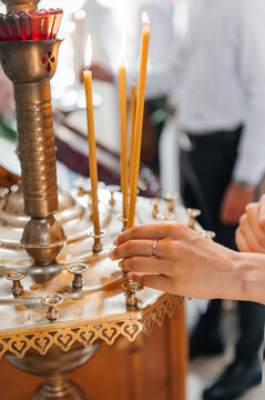 Close-up of hands holding a white embroidered baptismal towel (kryzhma) with a cross and dove, and a priest holding a prayer card during the ceremony.