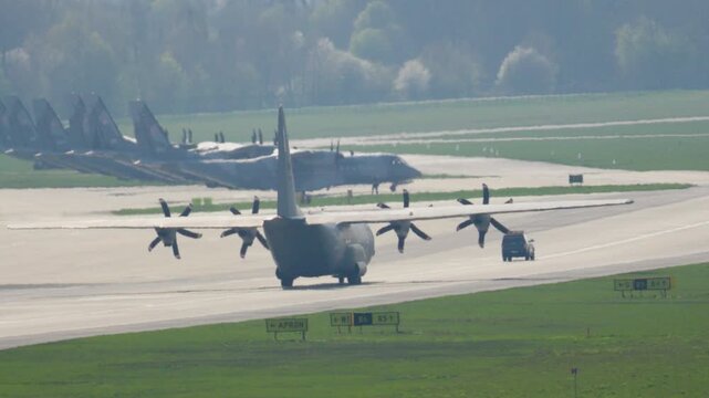 C-130 Hercules performs impressive landing maneuvers at the bustling airbase during a sunny day