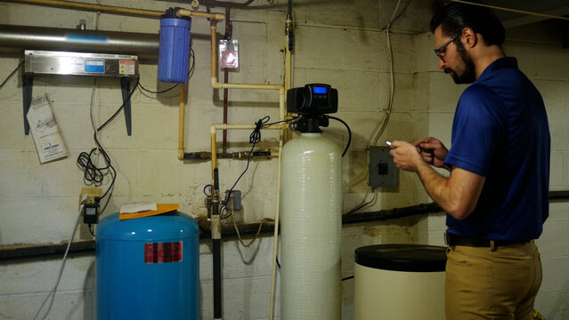 A Plumbing or Well Specialist Takes Notes on Indoor Water Filtration System 