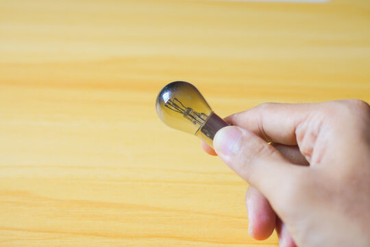 Hand holding light bulb on wood background