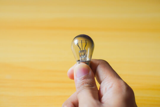 Hand holding light bulb on wood background