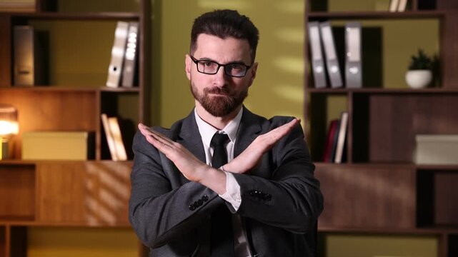 Man shaking head and crossing arms expressing disagreement in office
