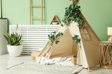 Cute wigwam with leaves and blanket in stylish child's room © New Africa